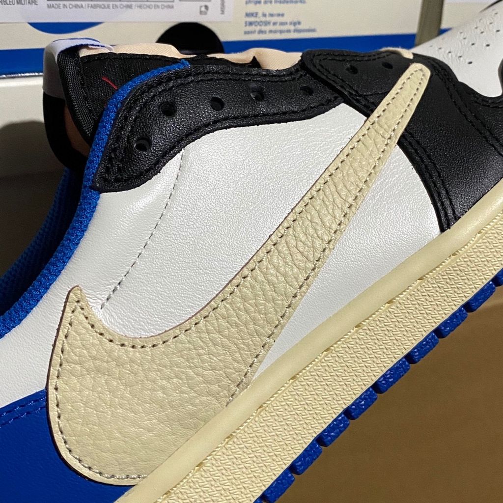 Shop Fragment Design x Travis Scott x Air Jordan 1 Low OG SP DM7866-140 in White, Black, Royal and Sail with reverse Swoosh and collaborative heel branding.