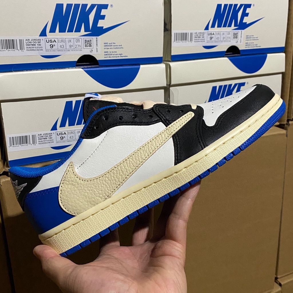 Shop Fragment Design x Travis Scott x Air Jordan 1 Low OG SP DM7866-140 in White, Black, Royal and Sail with reverse Swoosh and collaborative heel branding.