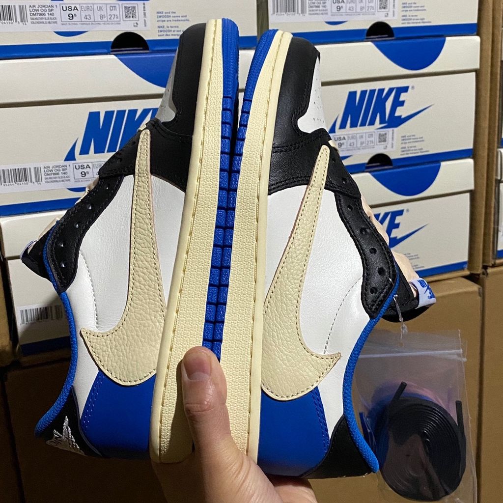 Shop Fragment Design x Travis Scott x Air Jordan 1 Low OG SP DM7866-140 in White, Black, Royal and Sail with reverse Swoosh and collaborative heel branding.