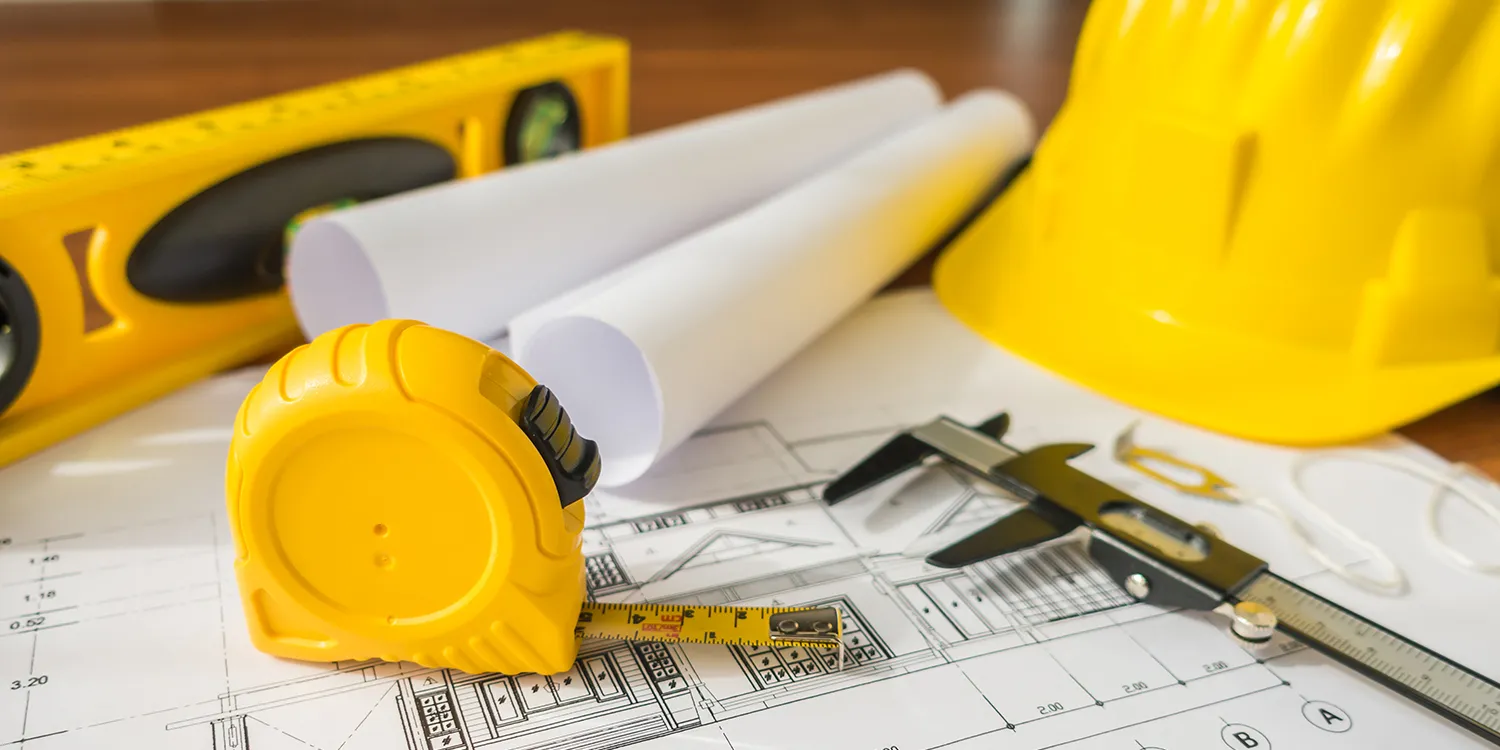 construction-plans-with-yellow-helmet-drawing-tools-bluep