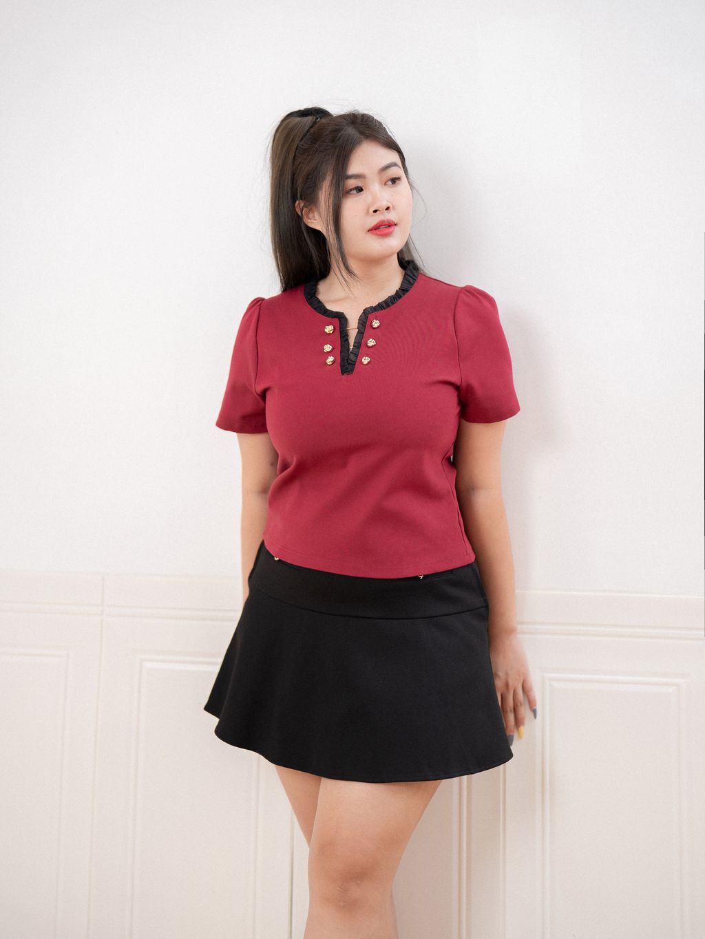 Plus size woman posing confidently in wine red Golden Petal Top with gold accents.