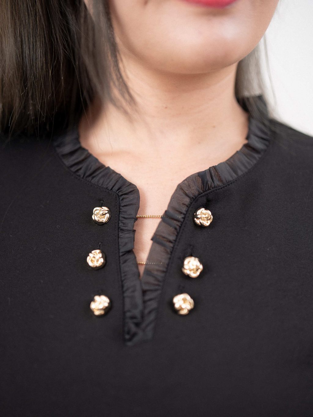 Close-up of neckline detail on plus size Roma knit top with elegant trim.