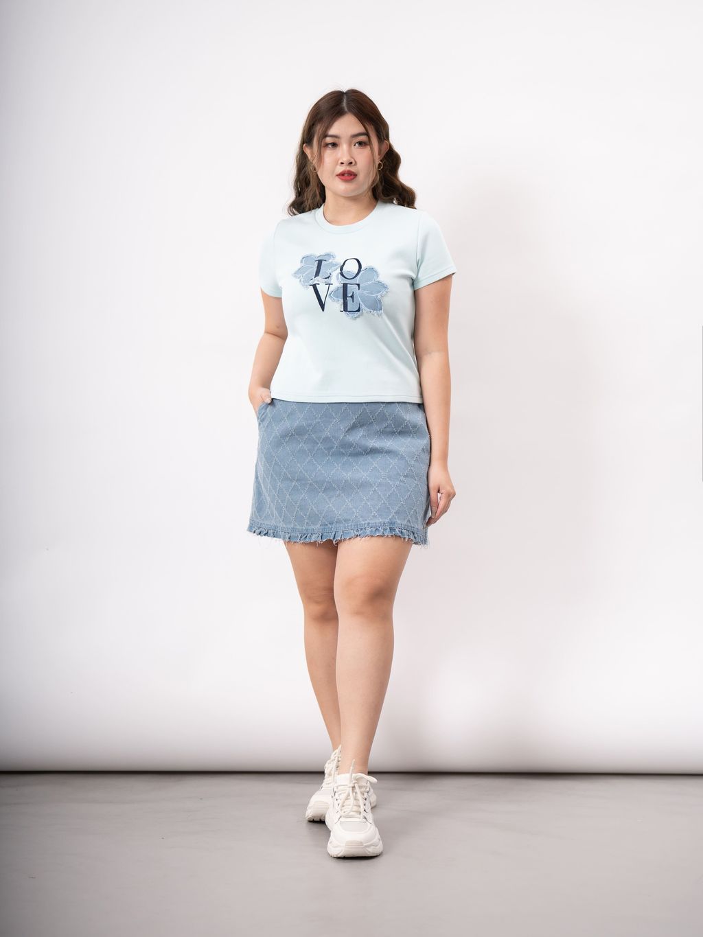 Plus-size model wearing white tee with denim flower and LOVE text