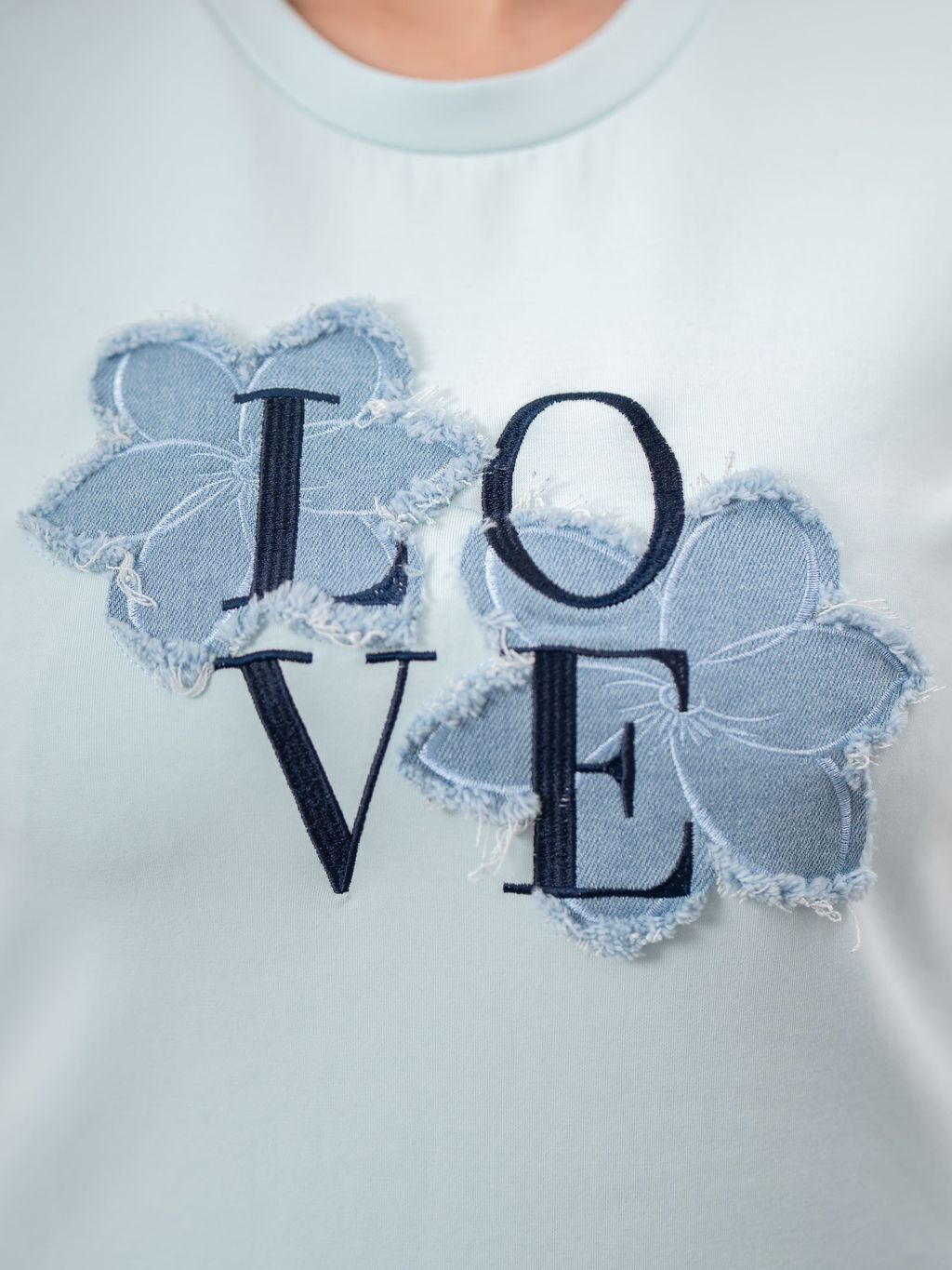 Close-up of LOVE embroidery with frayed denim flower patches