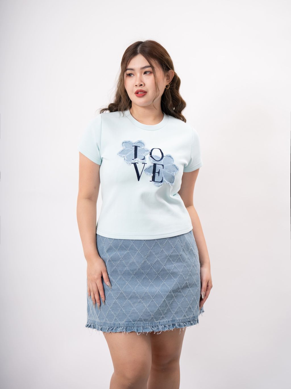 Full-body shot of model in white LOVE tee and denim mini skirt