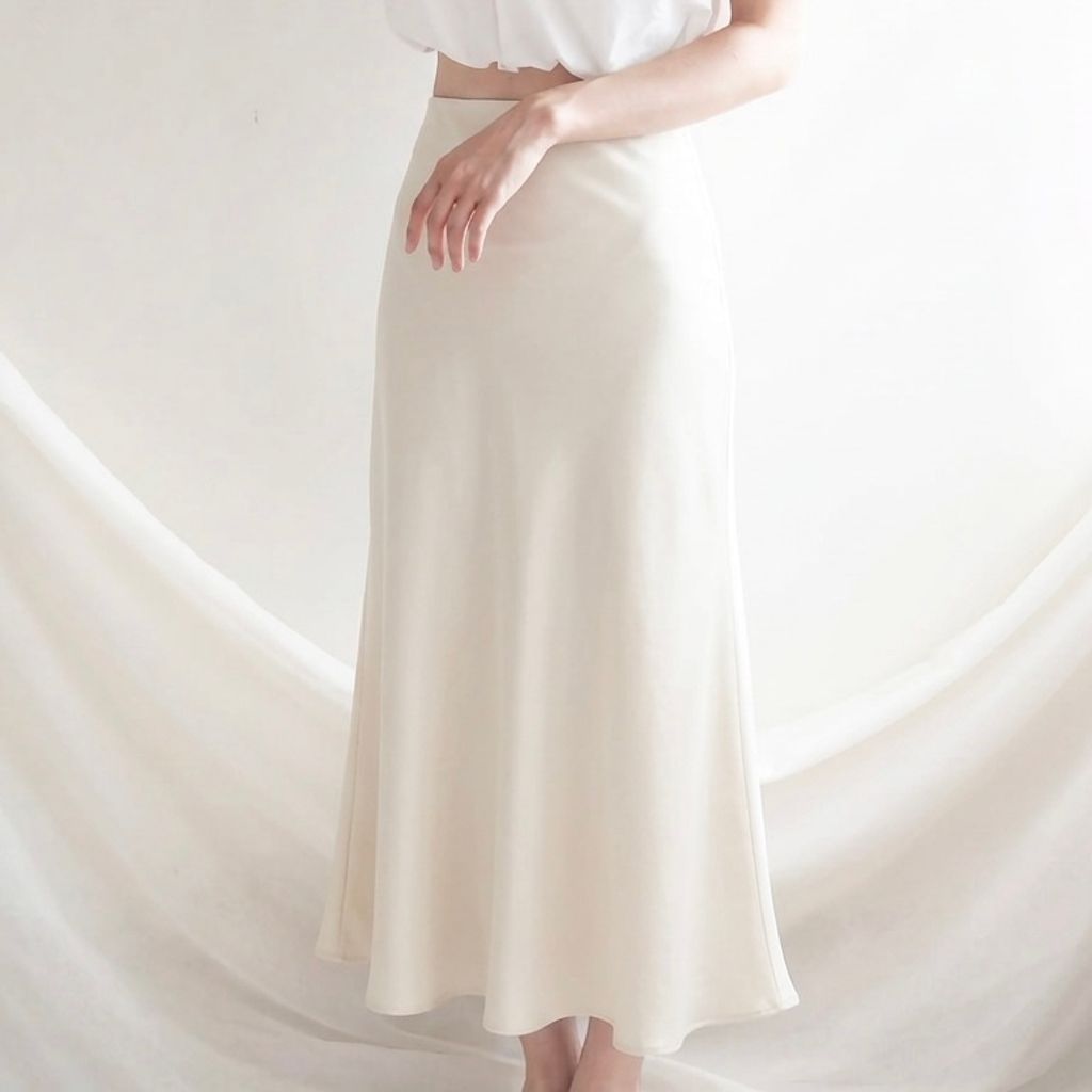 Output_an_image_of_the_provided_image_in_a_centered_square_composition_replacing_the_current_skirt_with_the_long_flowing_beige_maxi_skirt_from_the_other_reference_image_ensuring_natural_fabric_drape_and_realistic_lighting_ultra_high_resolut