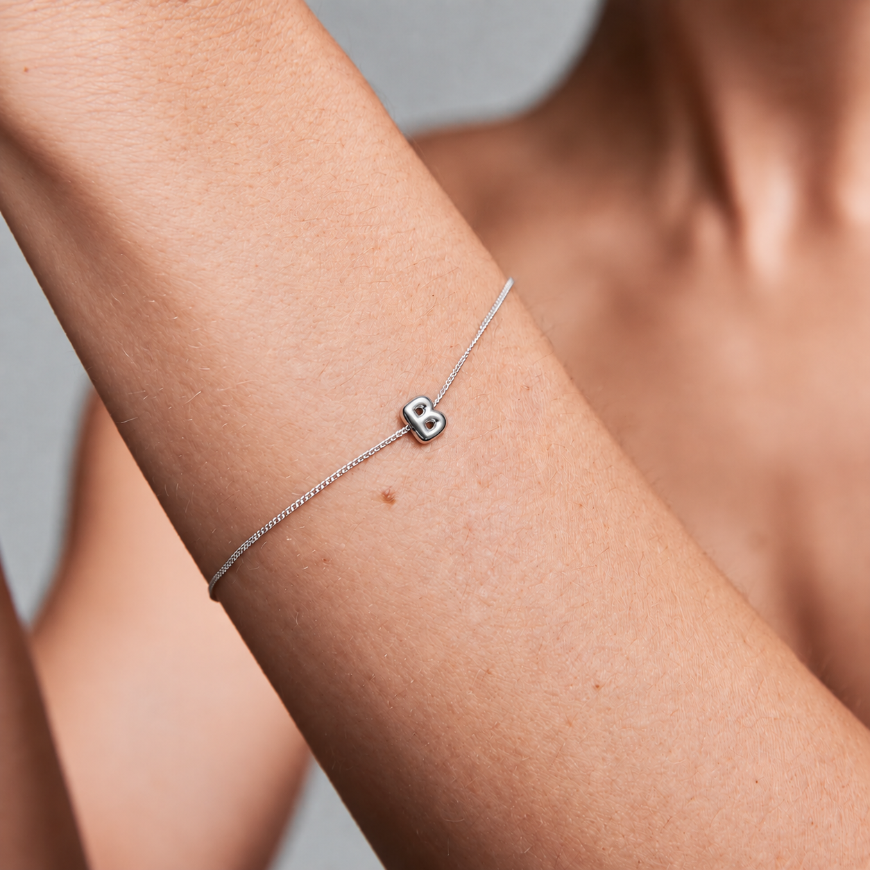 Silver B charm bracelet on wrist
