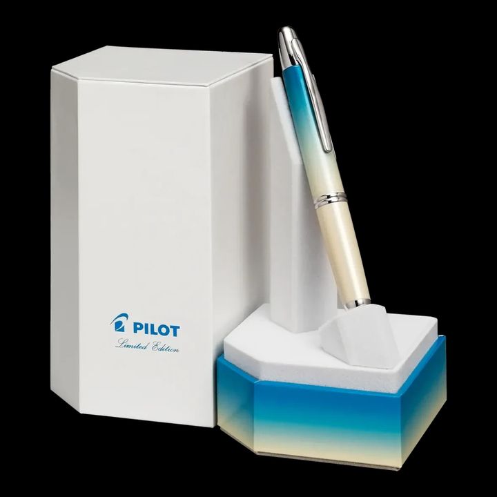 A PILOT Capless retractable fountain pen, featuring an ombre design that transitions from turquoise to white, displayed upright in a giftbox featuring the same ombre design.