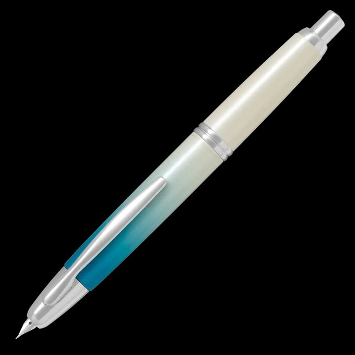 A PILOT Capless retractable fountain pen, featuring a limited edition barrel design called Seashore, that transitions from deep sea turquoise to a shimmering white, evoking pure sand on a coastline.