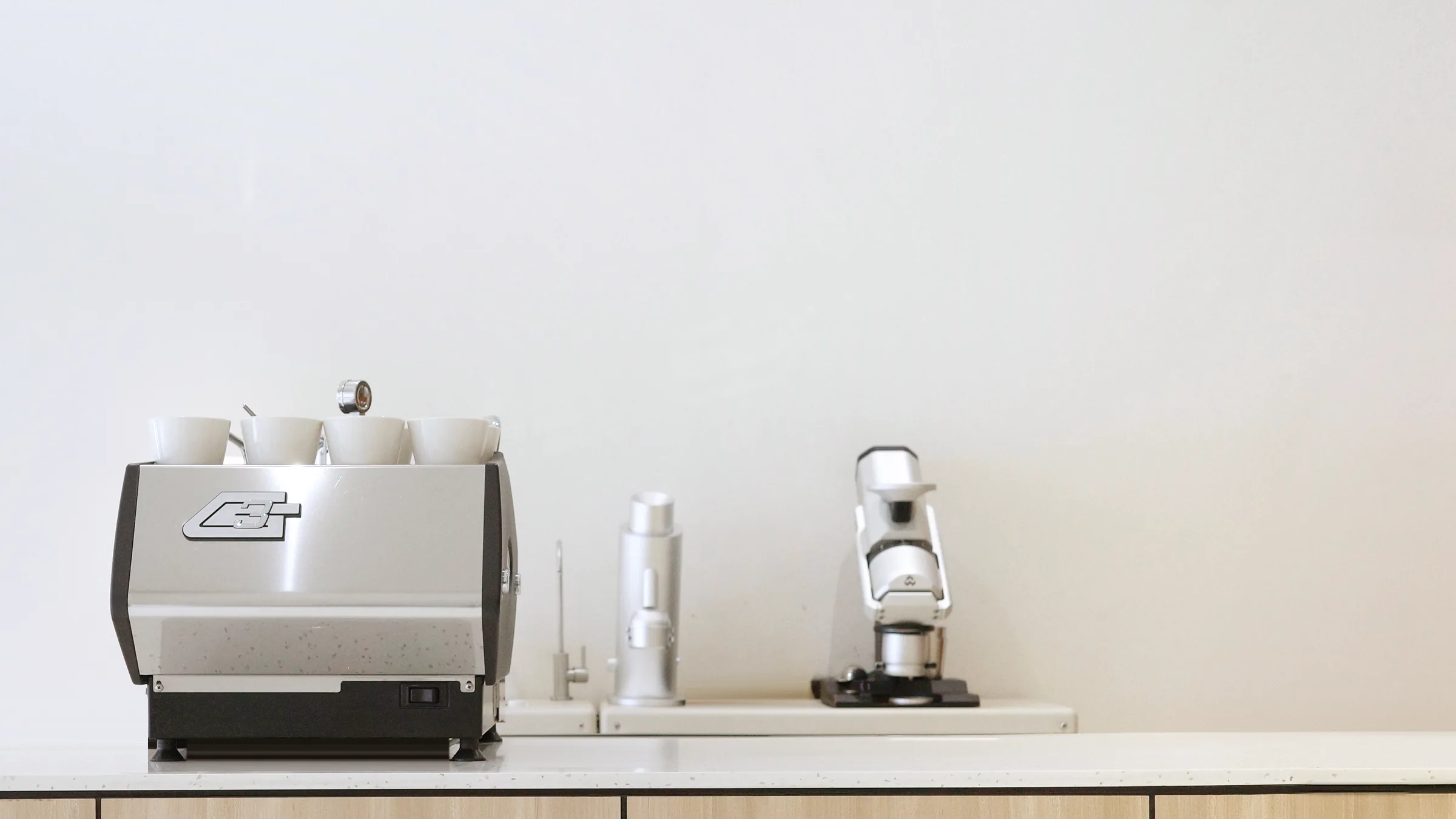 Brewsmith espresso bar with espresso machine, cups and grinders on a white counter
