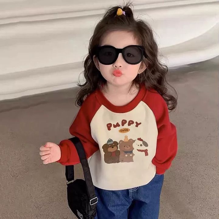 女童穿米白底紅肩袖PUPPY小狗圖案上衣，搭配墨鏡與牛仔褲