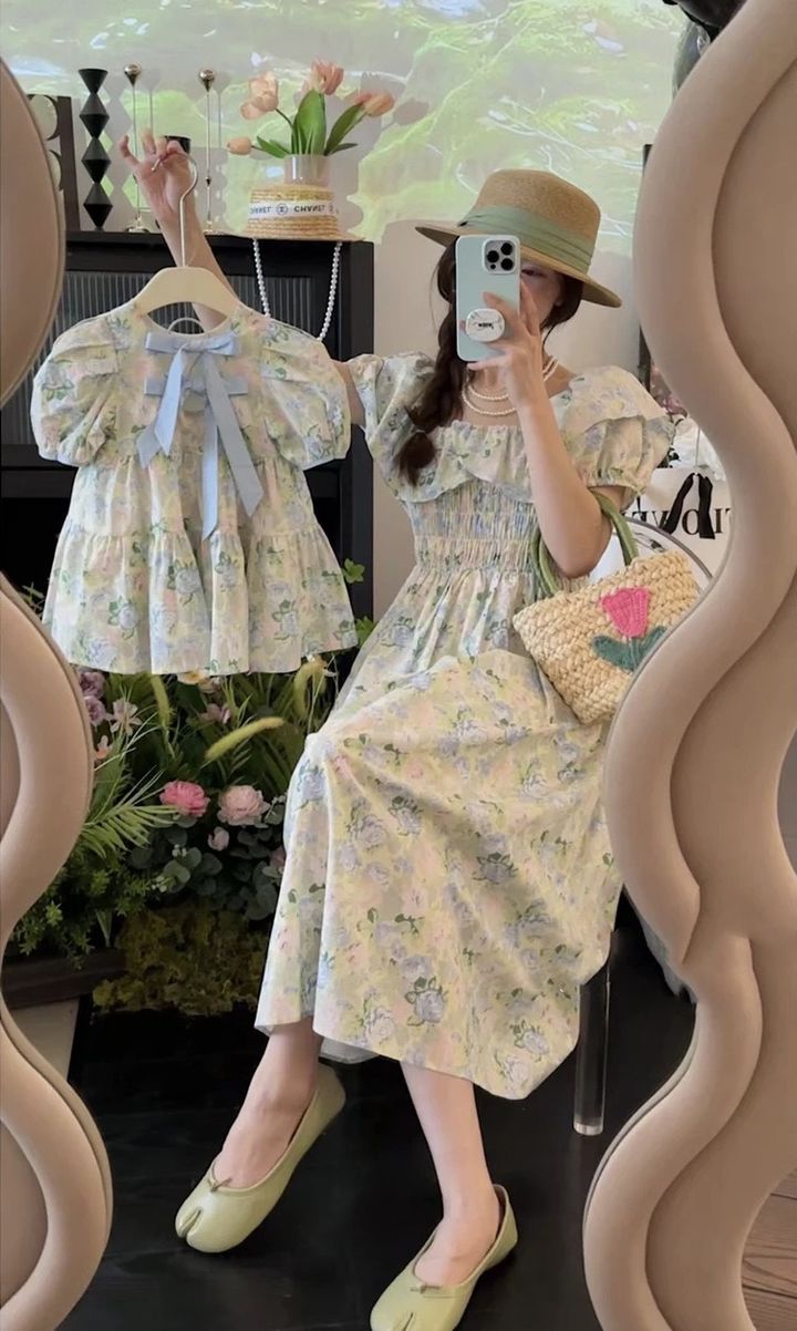 媽媽穿淺色碎花泡泡袖洋裝坐姿自拍，手持同款女童洋裝