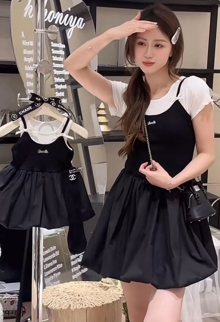 媽媽穿白色短袖拼接黑色吊帶造型洋裝，手持同款女童洋裝自拍