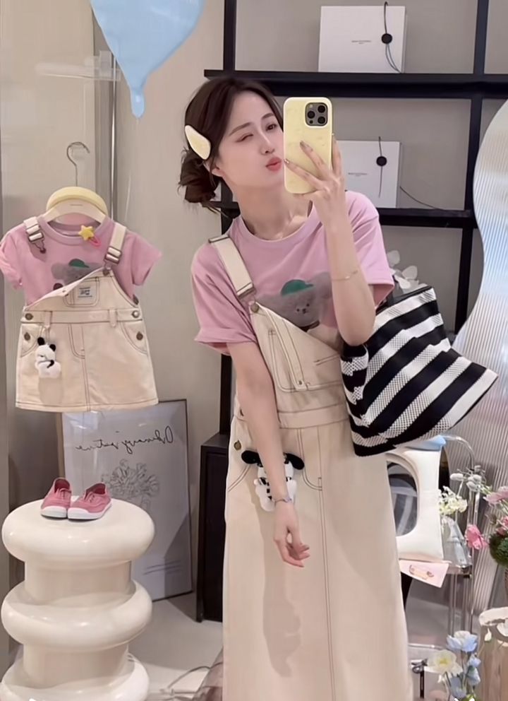 媽媽穿粉色小熊圖案T恤搭米白吊帶長裙鏡前自拍，旁邊展示女童款