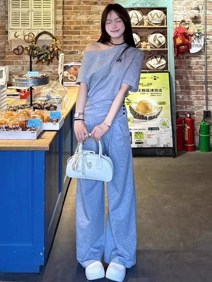 灰色斜肩短袖上衣與寬褲套裝，店前全身穿搭