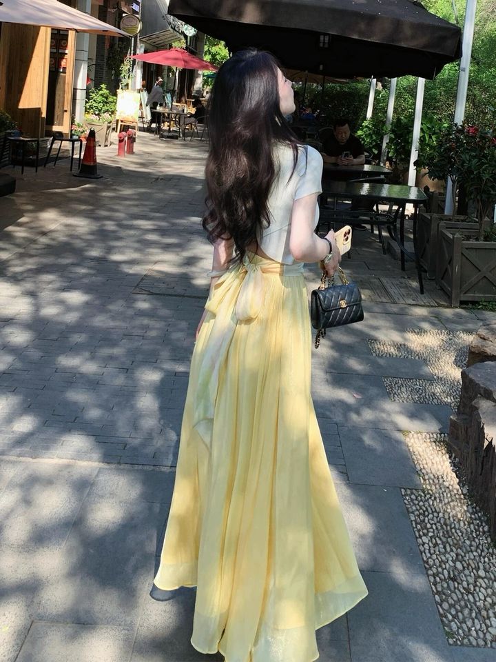 白色短袖上衣搭配鵝黃色長裙，戶外背面全身穿搭