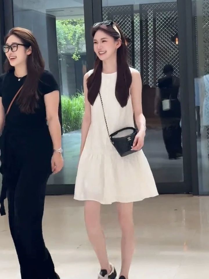 白色無袖短洋裝，與黑衣同行者一起行走的穿搭