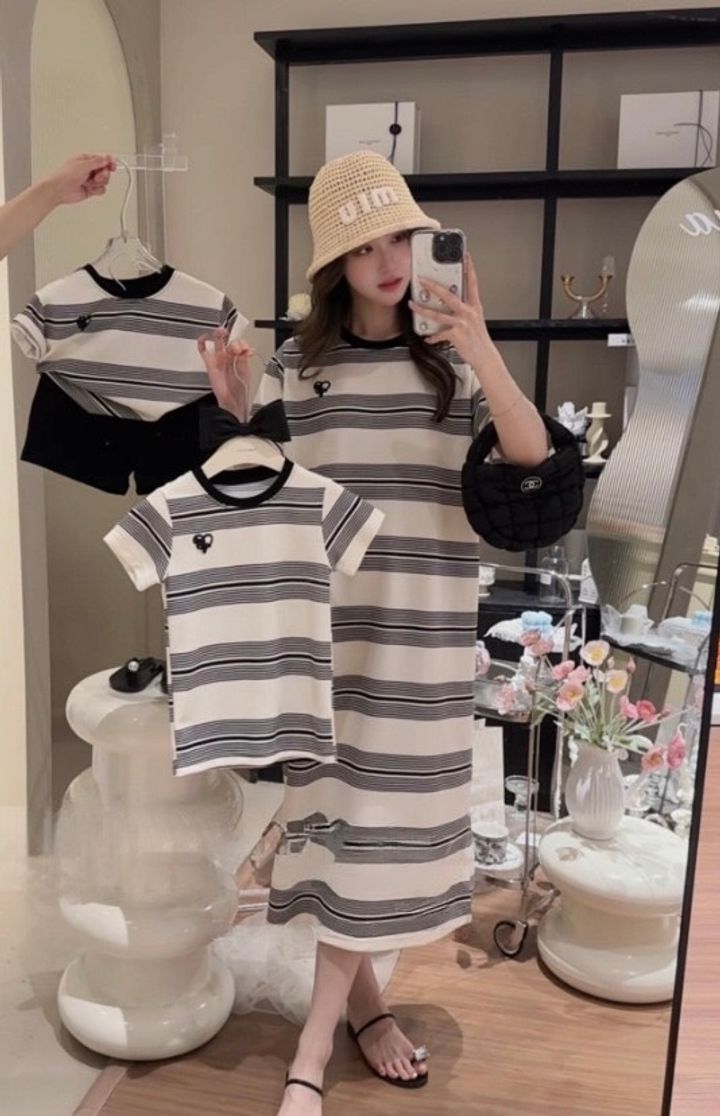 媽媽穿黑白橫條紋短袖長洋裝，手持同款童裝展示親子穿搭