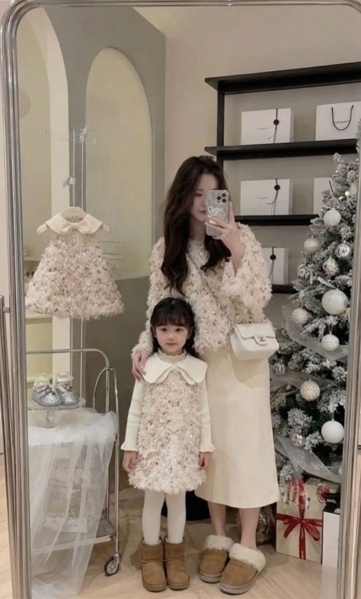杏色毛絨感上衣與女童背心裙，母女在聖誕樹旁鏡前合照