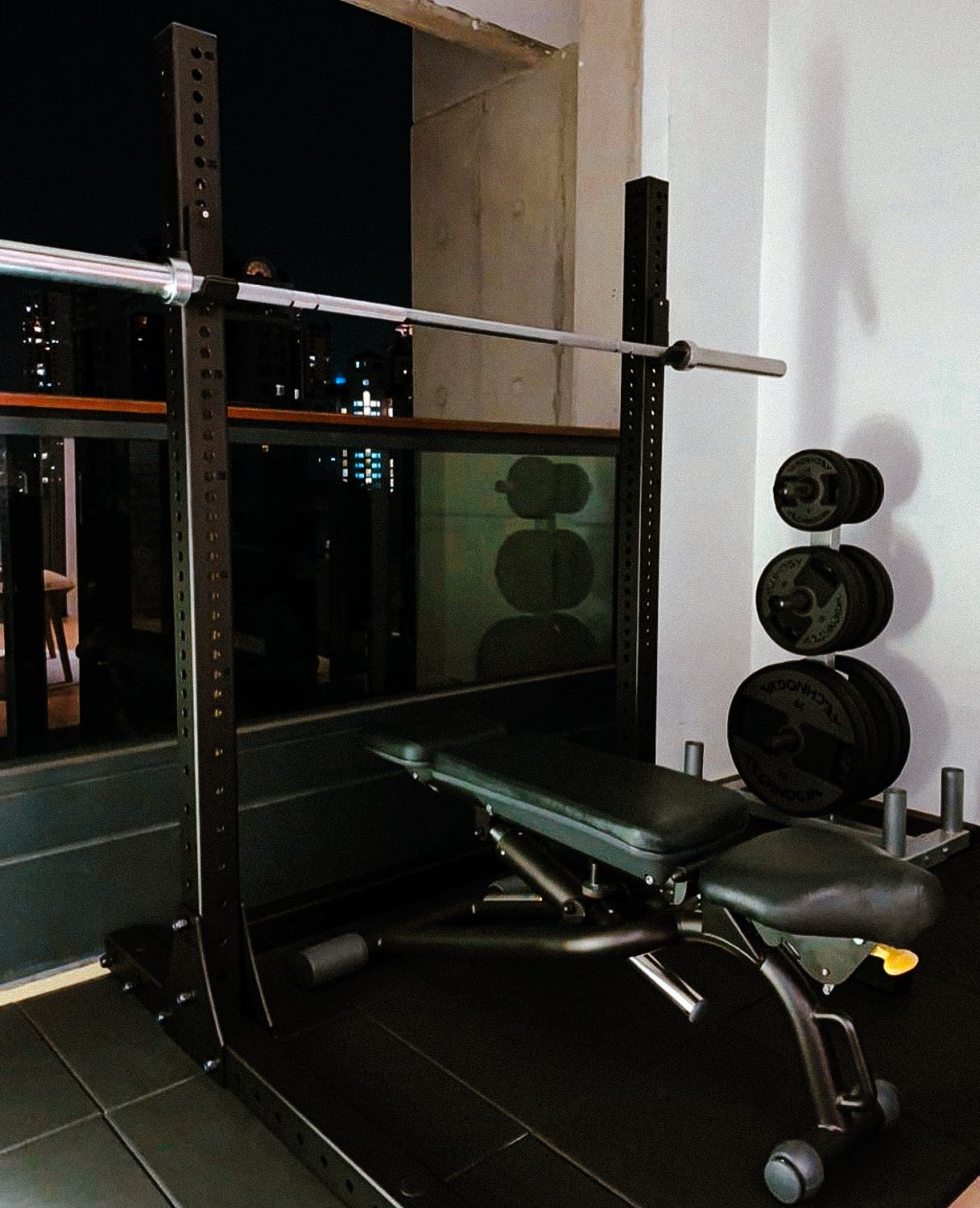 An Eleiko rack, bench and plates by a window at night