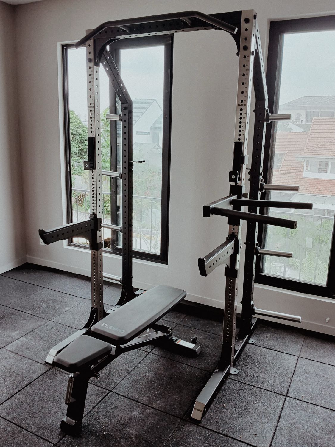 A home gym with an Eleiko rack and bench by tall windows