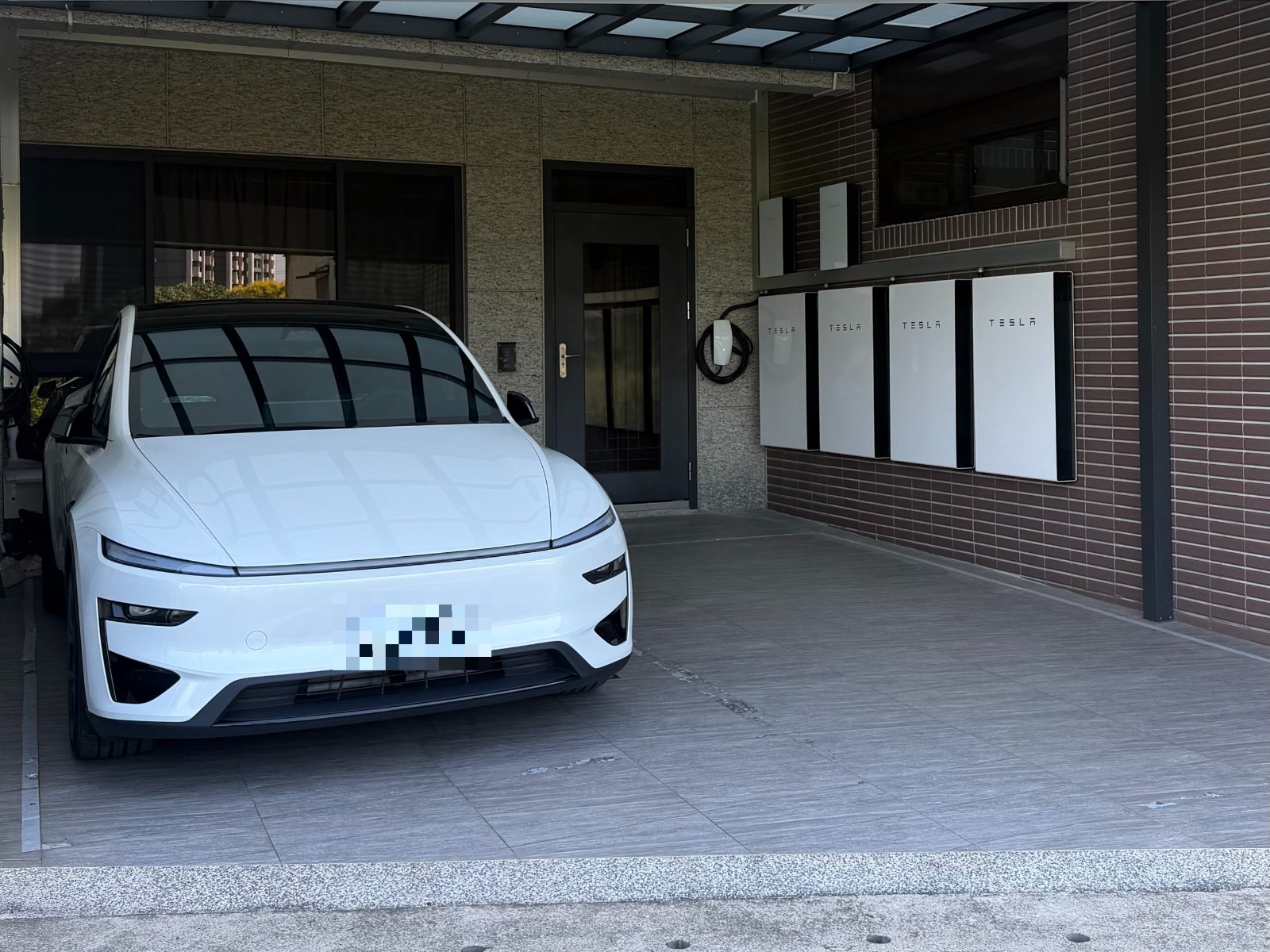 崧象智能安裝實績：住宅車庫內的 Tesla Wall Connector 與四套 Tesla Powerwall，旁邊停著白色電動車