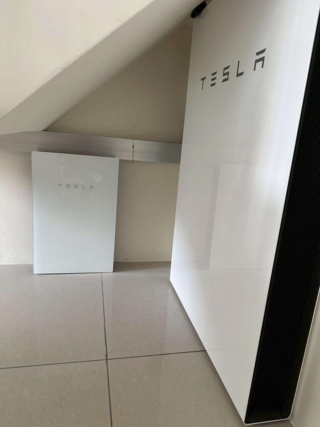 崧象智能安裝實例：透天頂樓斜屋頂下的室內空間，牆邊與近處各安裝 Powerwall，近處可見側邊散熱紋路