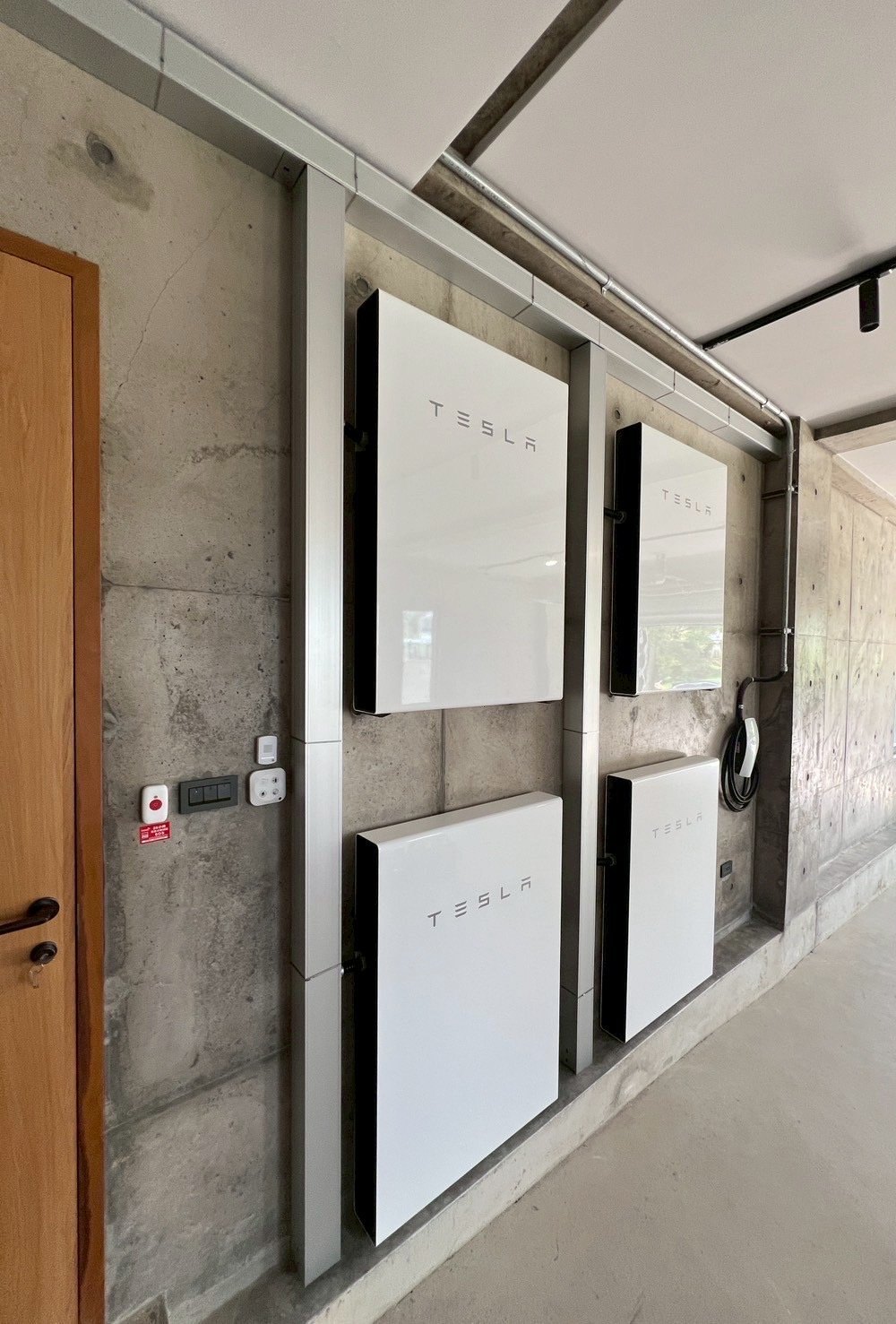 崧象智能安裝的 Powerwall×4,分成左右兩組、上下壁掛在清水模牆面,鋁製線槽整齊,旁邊是電動車充電座