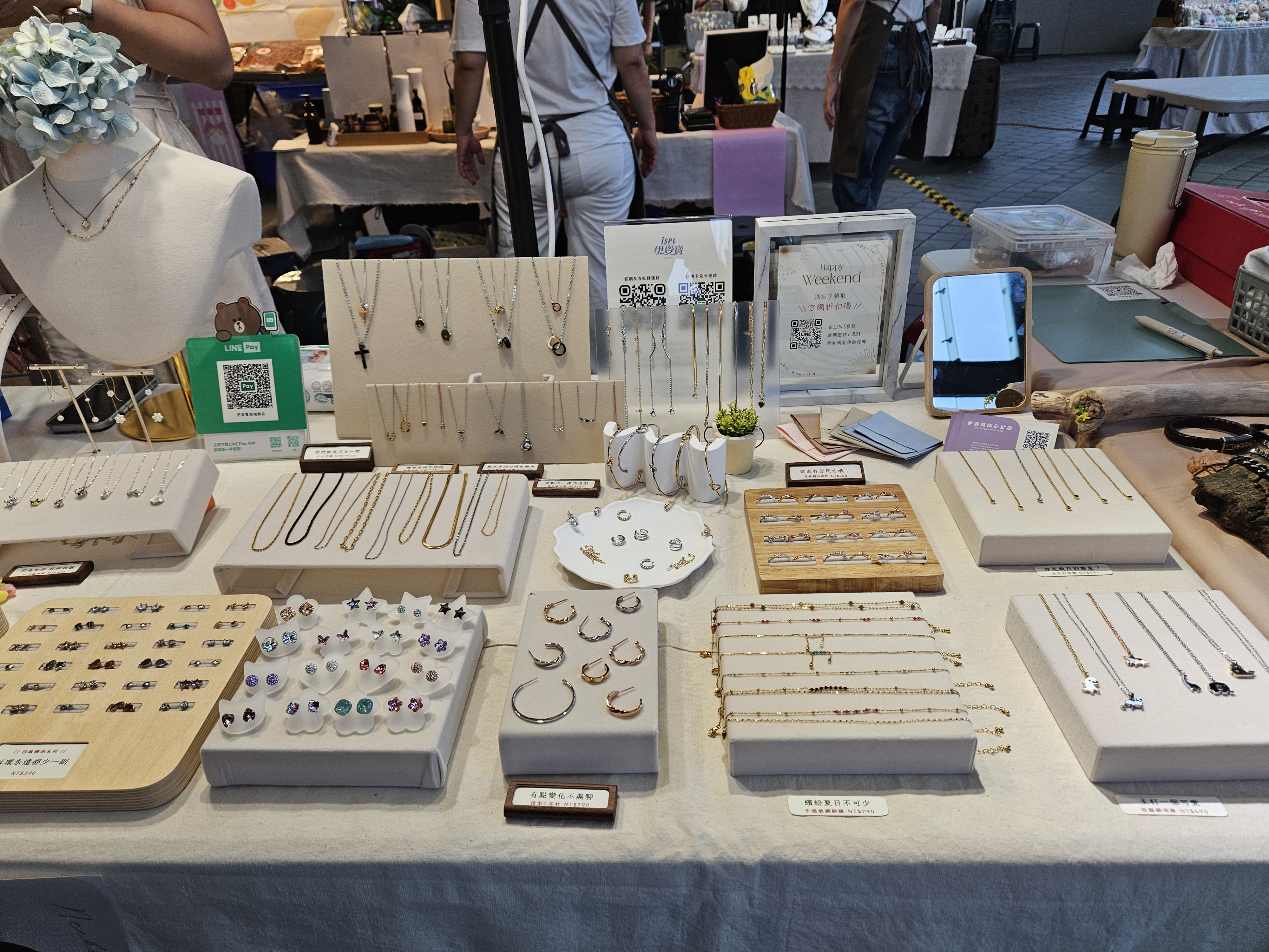 市集手作銀飾展示攤位，擺滿耳環、項鍊、戒指等飾品，設計簡約又有風格