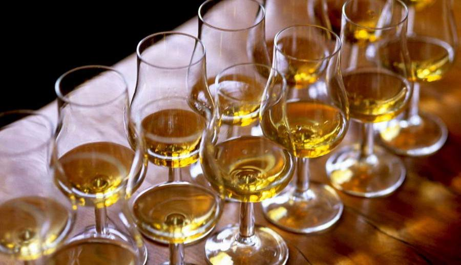 Whiskey tasting six glasses on wooden table.