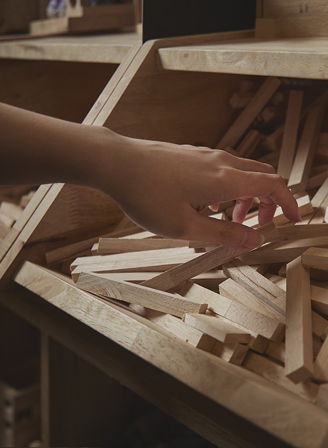 Hand picking wooden sticks at a woodwork class
