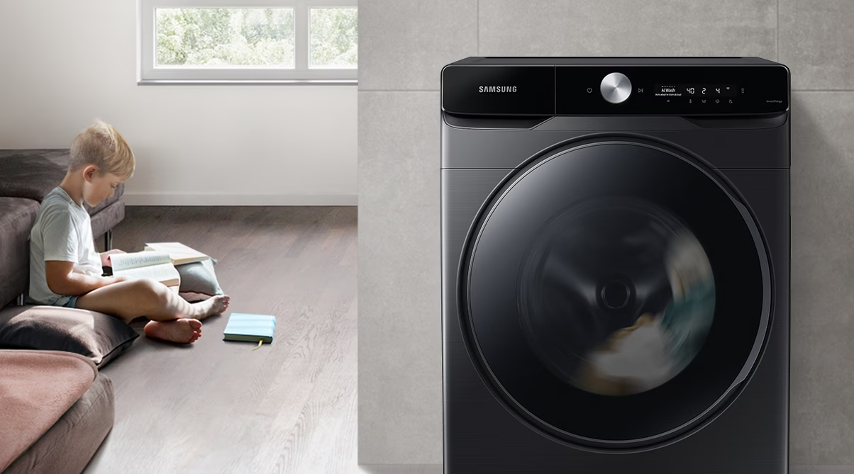 Description: The boy reads the book during the day in the living room, while the washer runs silently next to him.