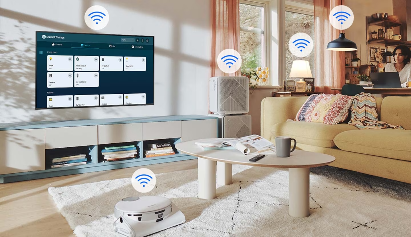 Description: The SmartThings UI is on display on the TV. Wi-Fi icons are floating on top of the TV, vacuum robot, air purifie and lights.