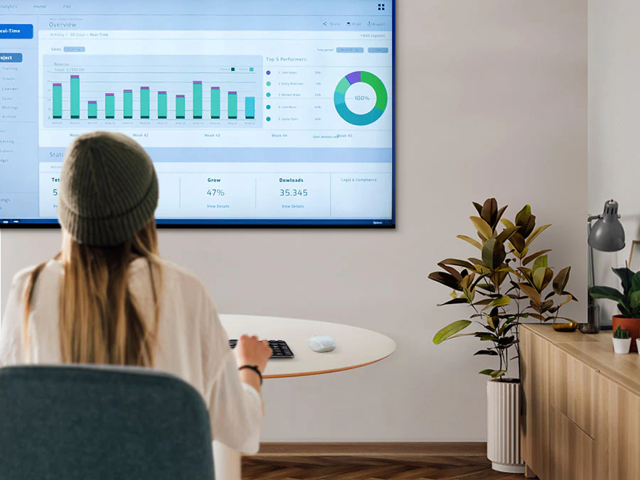 Description: A woman is working from home in her living room and typing on a keyboard that's connected to a samsung smart TV.