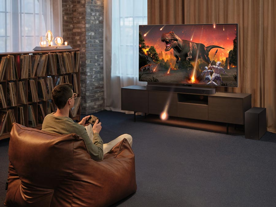 Description: A man enjoys an immersive 3D-like gaming experience with Samsung Soundbar Game Mode Pro.