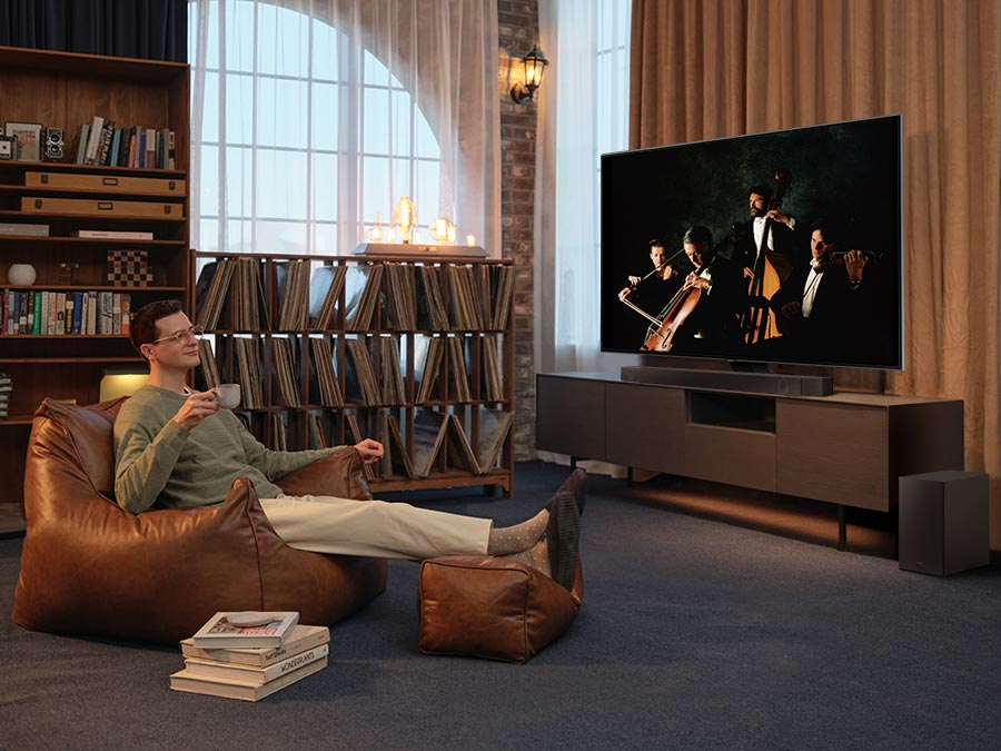 Description: A man enjoys an immersive symphony concert with Dolby Atmos Music in his living room.