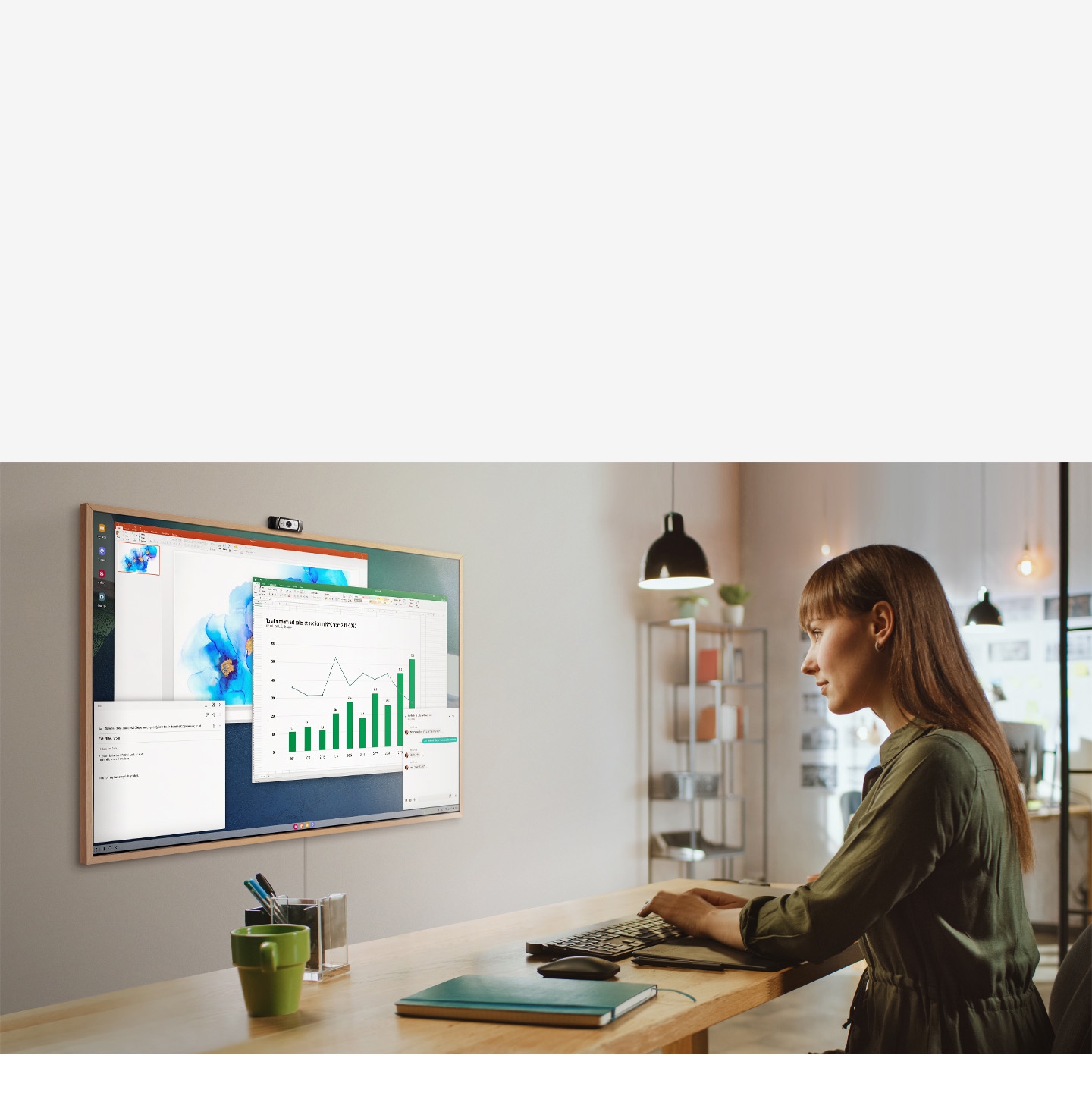 Description: A woman is using her office PC to do work on her TV screen at home. On the screen of The Frame are various office productivity windows.
