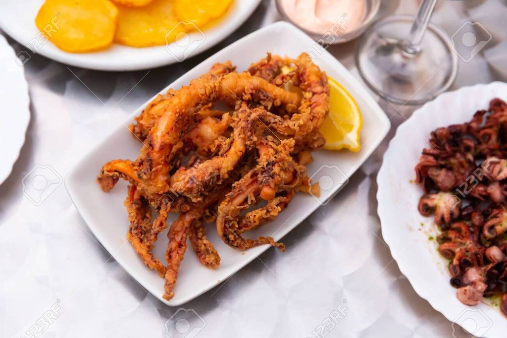 137257840-popular-spanish-tapa-rejos-fried-spicy-tentacles-of-squid-served-with-lemon-slice-and-sauces