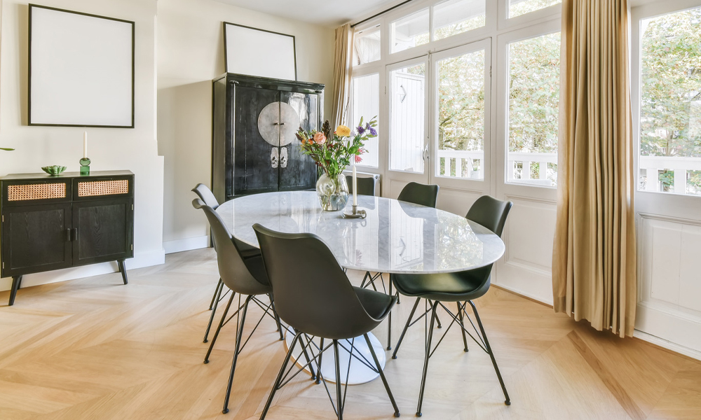 White glass oval dining table with black dining chairs