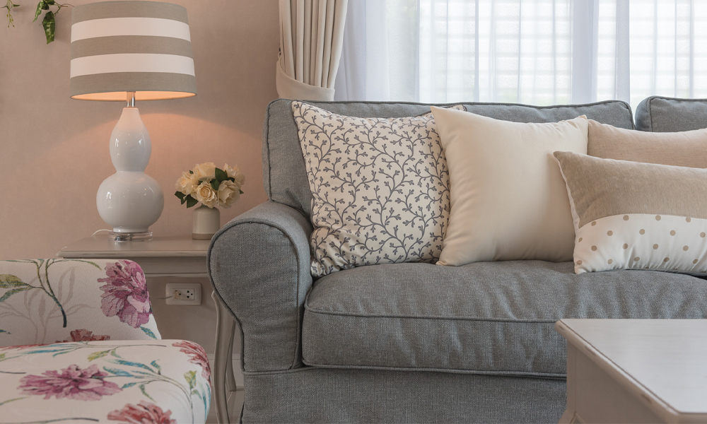 Soft grey sofa with pastel colour throw pillows in minimalist living area