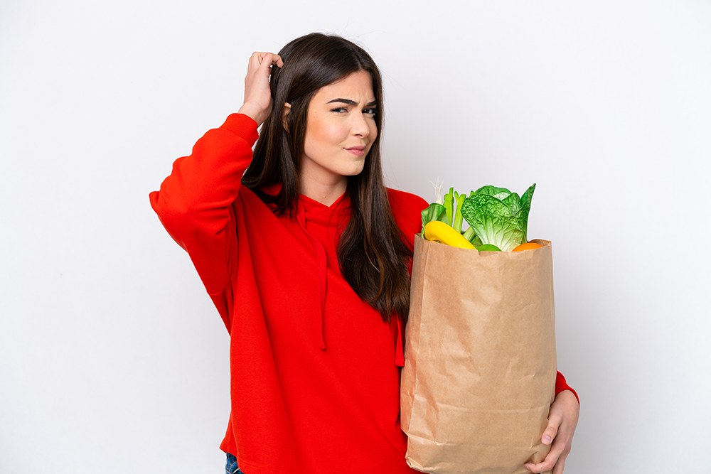 young-brazilian-woman-holding-grocery-shopping-bag-isolated-white-background-having-doubts