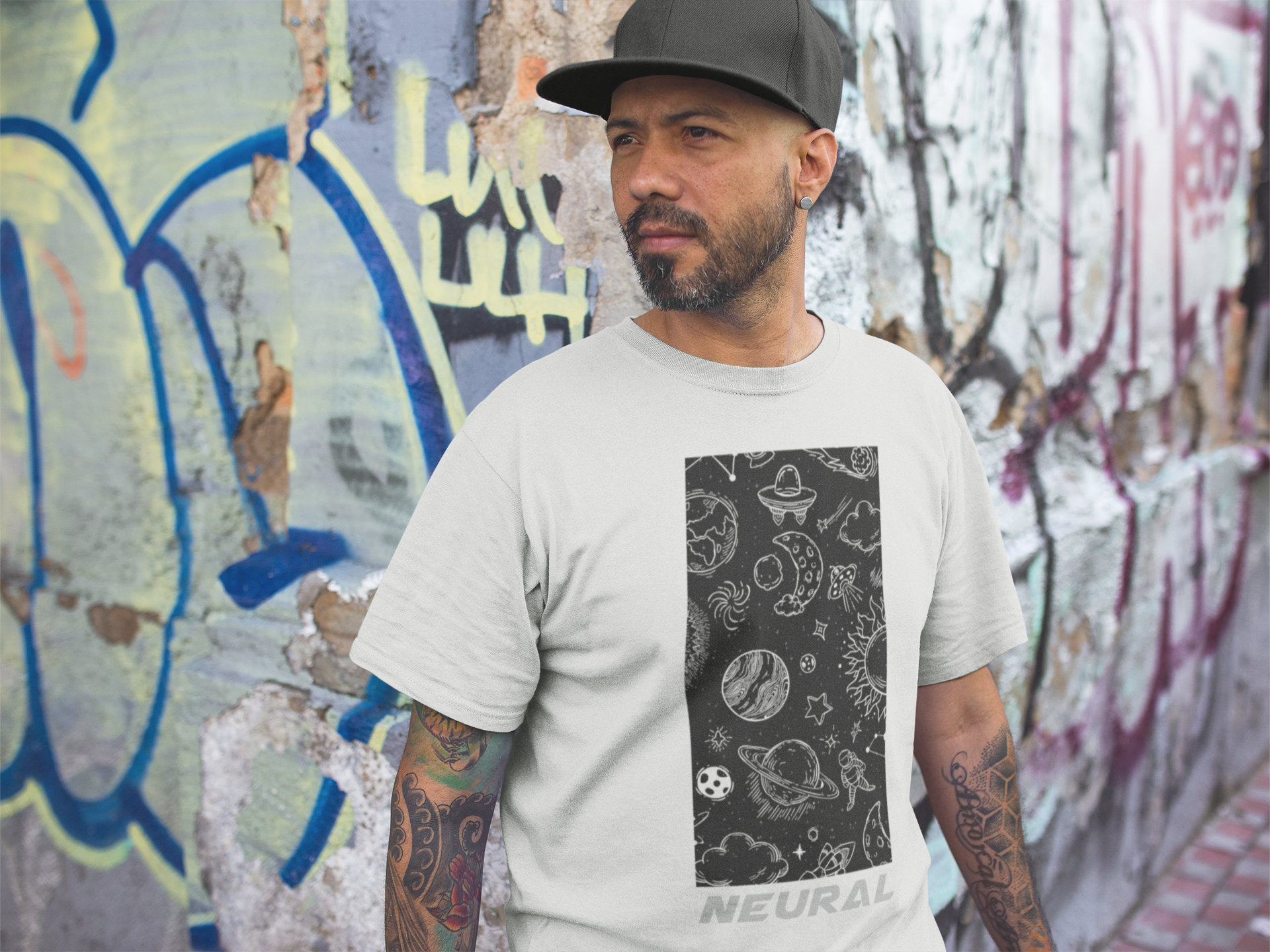 tattooed-middle-aged-man-wearing-a-round-neck-tee-mockup-against-a-graffiti-wall-a16976.png