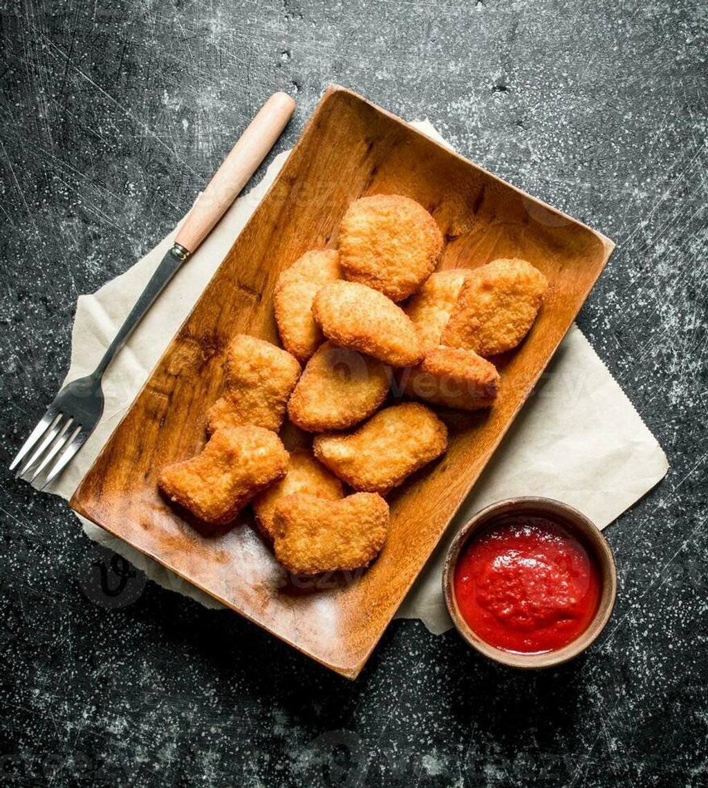 chicken-nuggets-on-a-plate-with-paper-and-tomato-sauce-in-a-bowl-photo