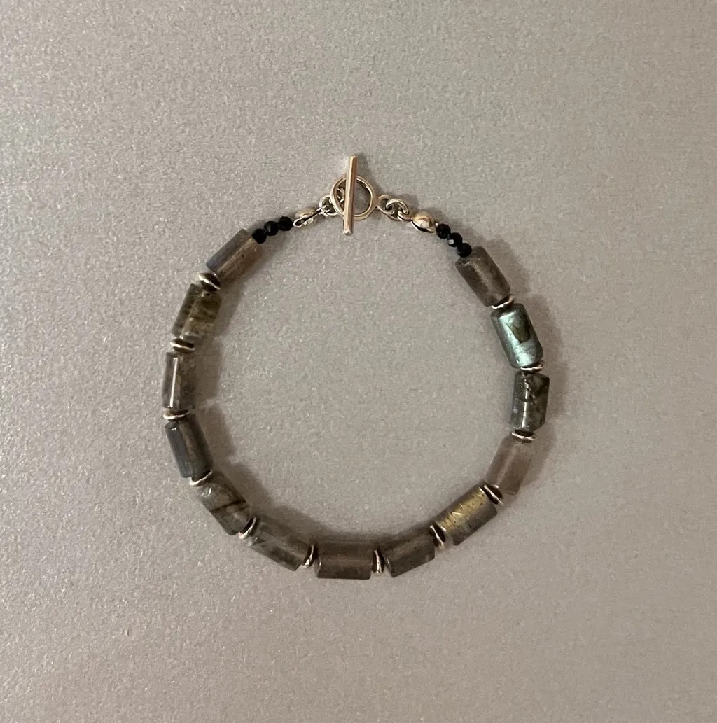 Roxane手鍊以圓柱狀拉長石與黑色尖晶石組成，搭配T型環扣，展現冷靜而神秘的風格