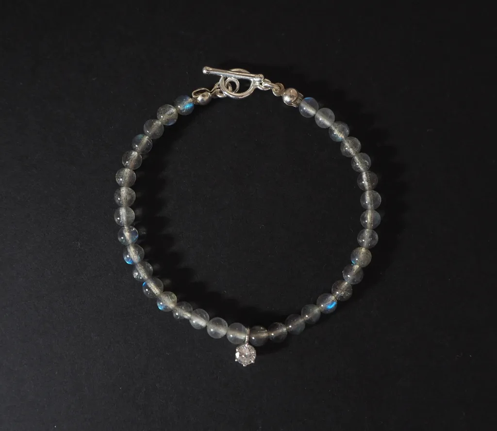 Gaia手鍊以拉長石為主體，中央墜飾為閃耀的鋯石，象徵夜光中的堅定信念