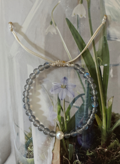 mira手鍊以閃爍著藍光的拉長石與淡水珍珠串成，可調式編繩設計讓配戴更輕鬆