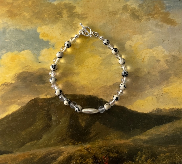 達爾馬提亞碧玉搭配白水晶的手鍊，呈現大麥町般的可愛斑點與清透光感，能帶來放鬆、輕盈與陪伴能量，適合容易想太多或情緒緊繃的人佩戴。