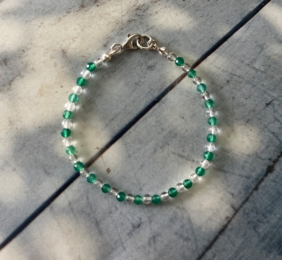 這款綠鉻透輝石與白水晶交錯串成的細緻手鍊，搭配 925 銀扣環；翠綠清透在日光下閃耀。