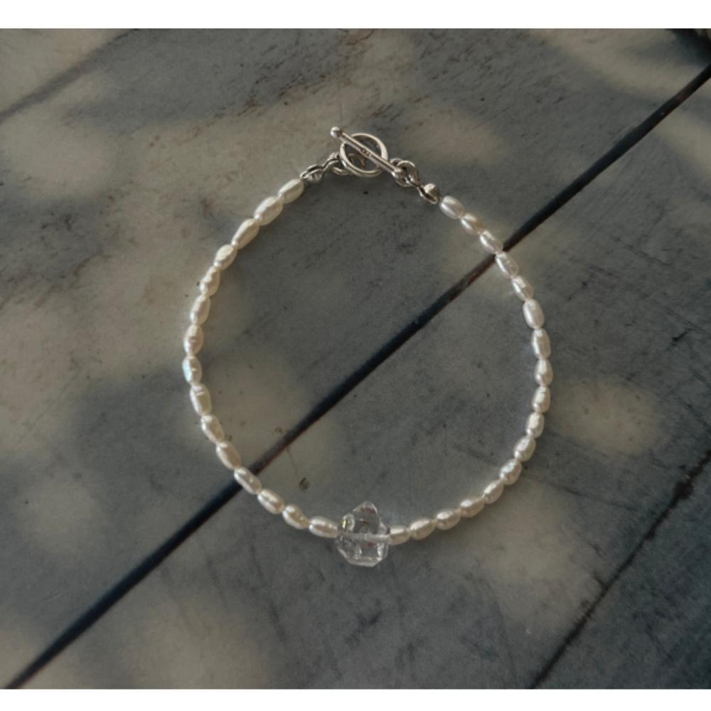 Matilda & Co.的 Luna Blanche 米粒珍珠與赫基蒙手鍊，搭配銀色 OT 扣，在自然光影下的細節特寫