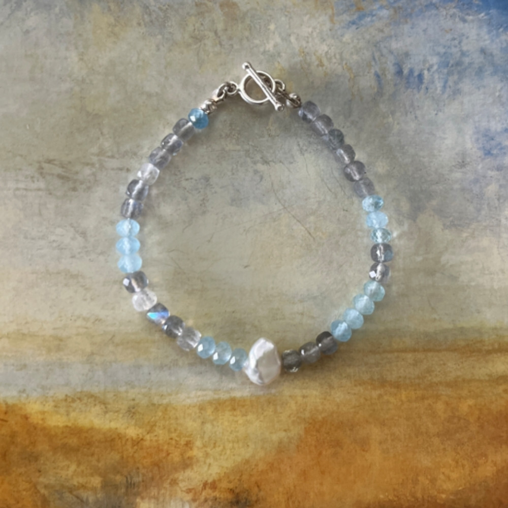 Matilda & Co. 方塊切割藍光拉長石與鑽切海藍寶串成的925純銀手鍊，呈現透亮藍灰色調。天然巴洛克珍珠，象徵深海平靜與靈感。